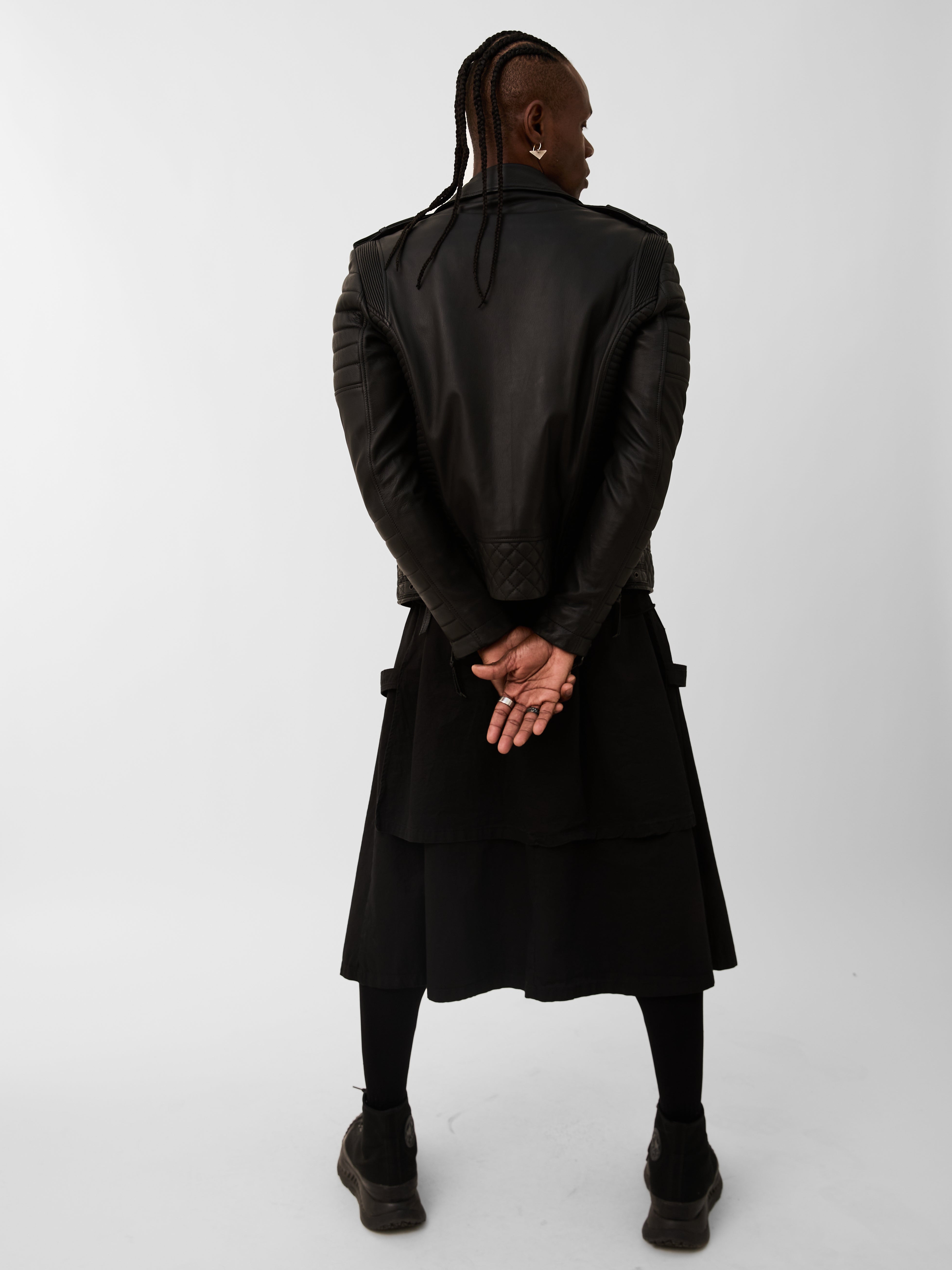 Person wearing a black biker jacket and skirt on a white background