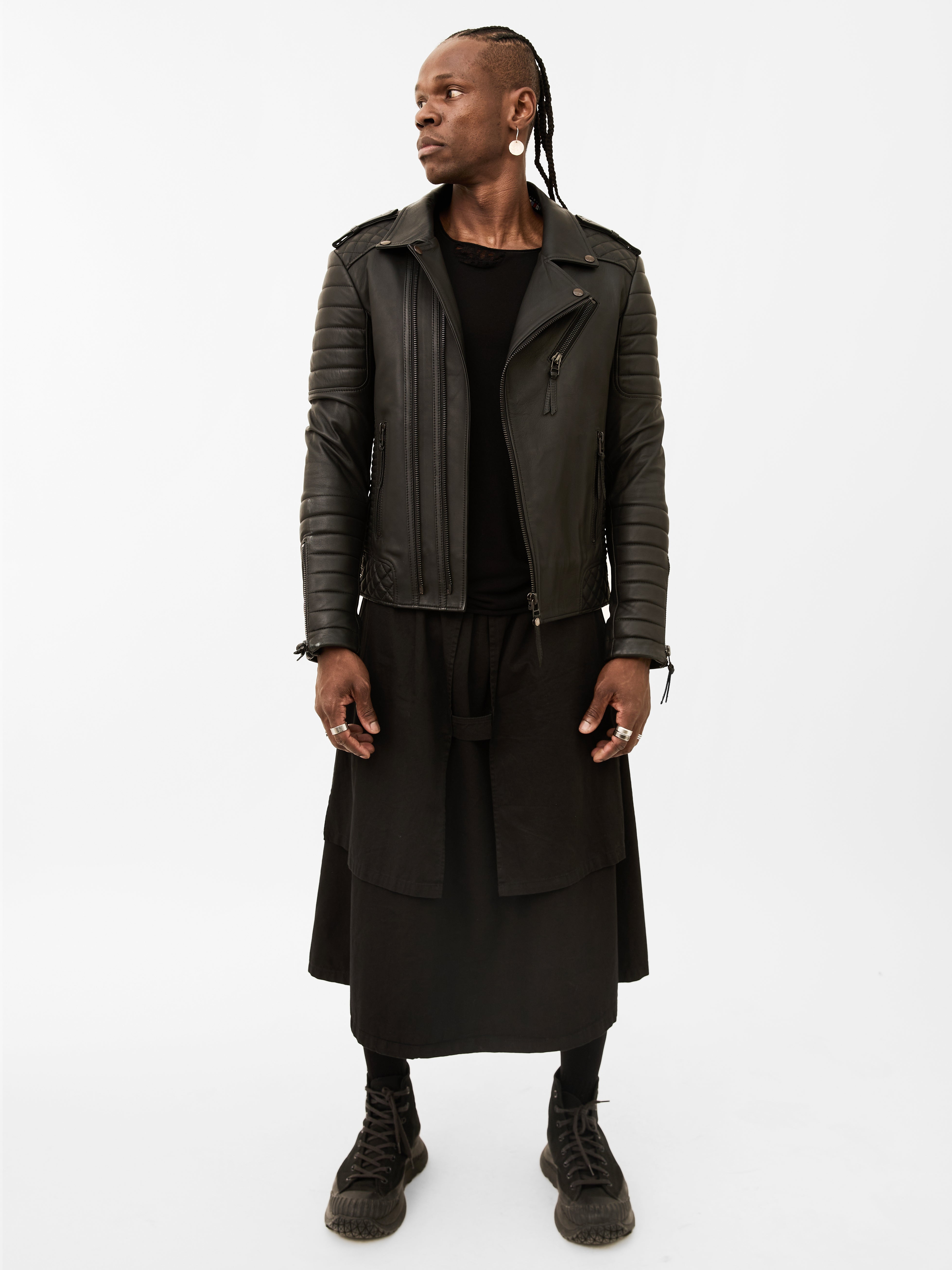 Man wearing a black leather jacket and black outfit on a white background
