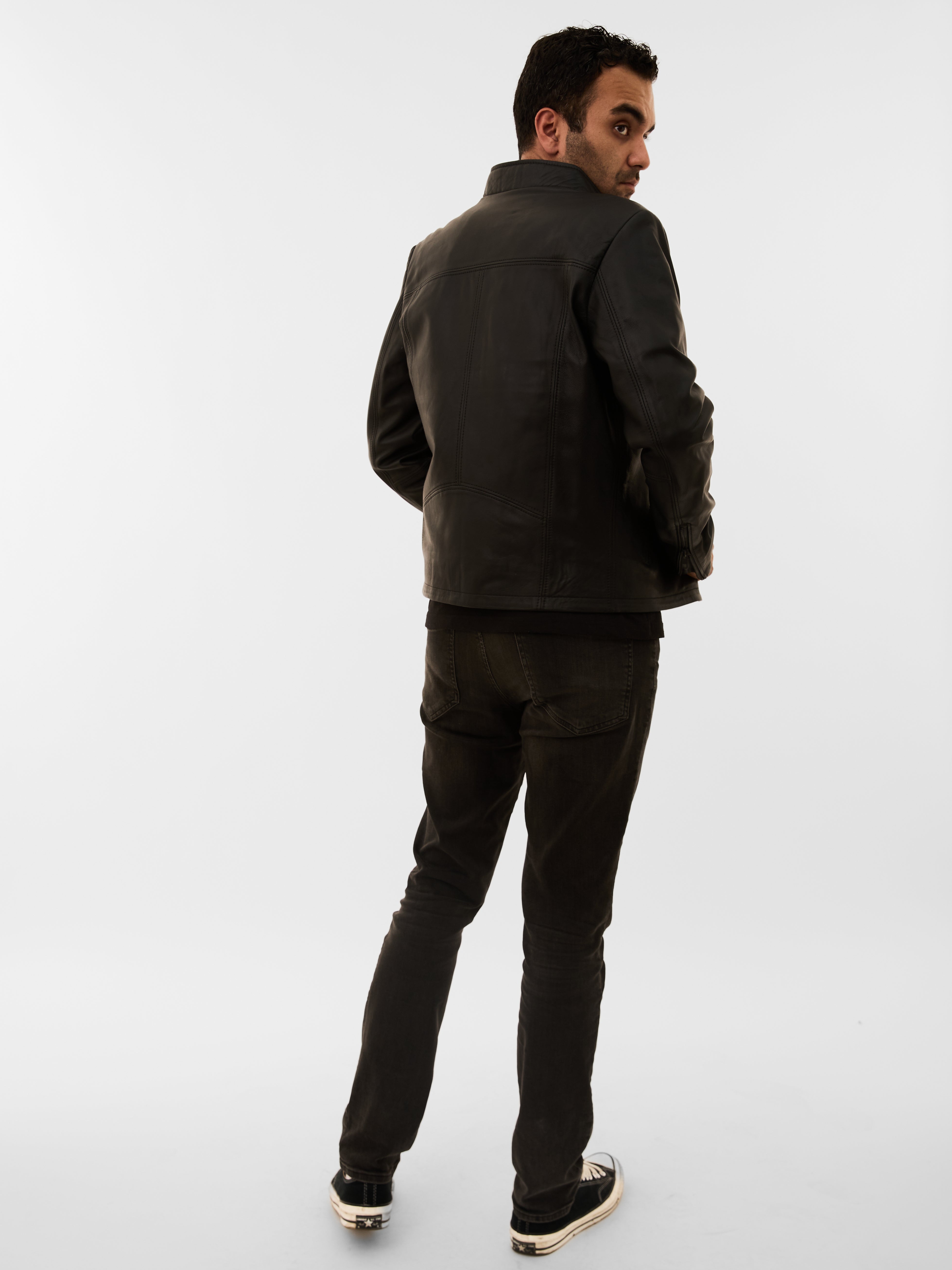 Man wearing a dark jacket and pants on a white background