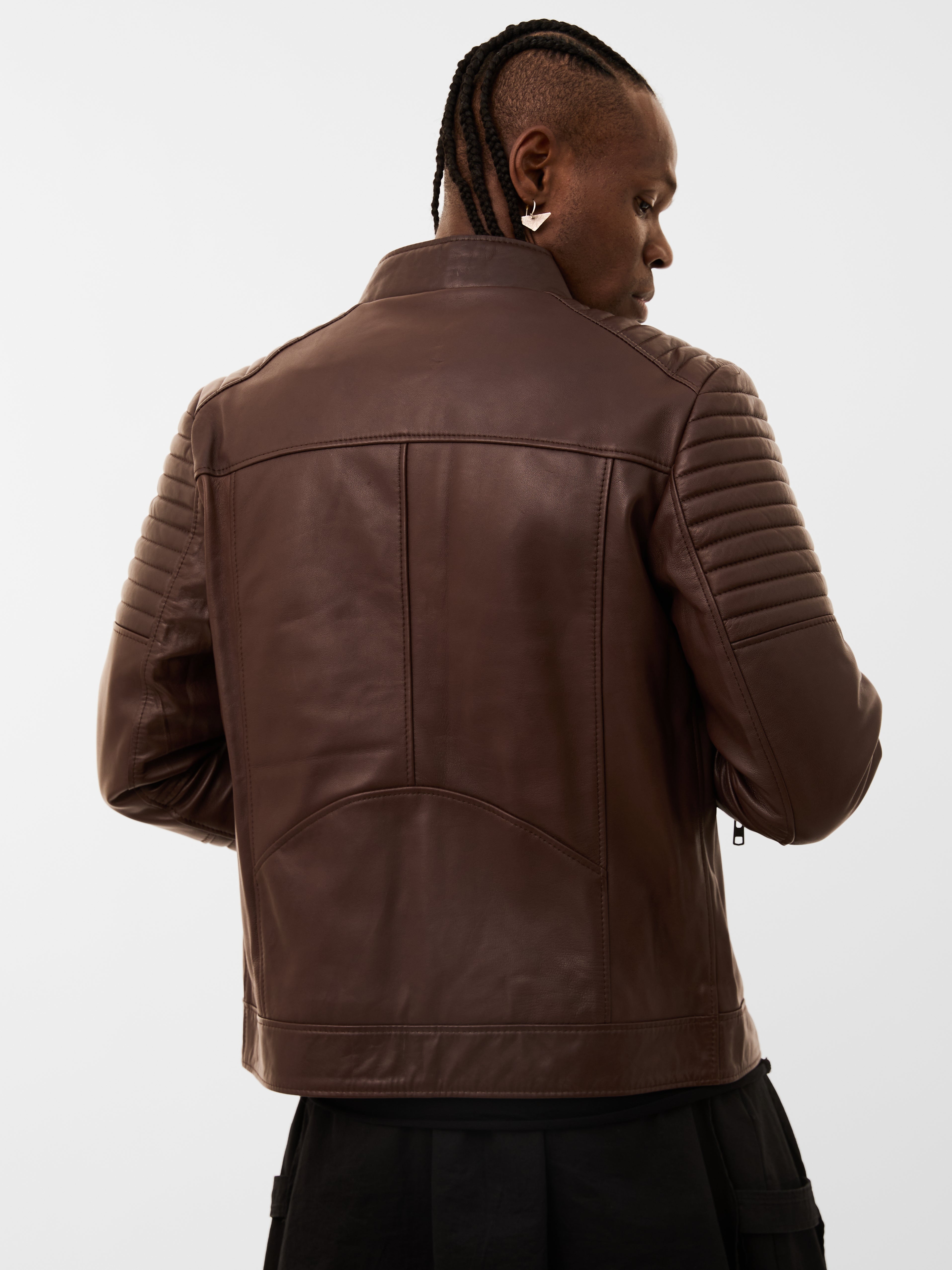 Person wearing a brown quilted leather jacket on a white background