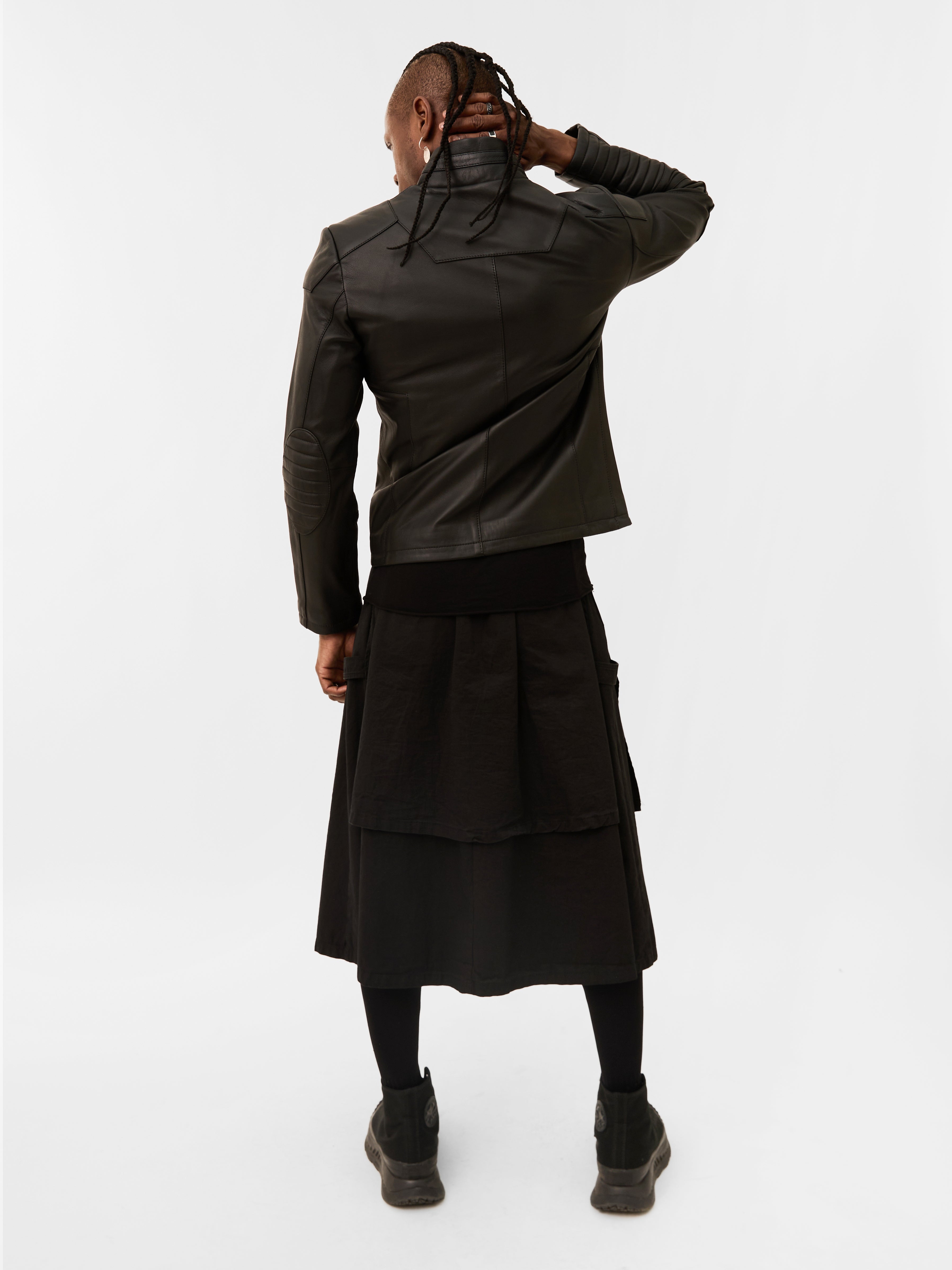 Person wearing a black leather racer jacket and skirt set on a white background