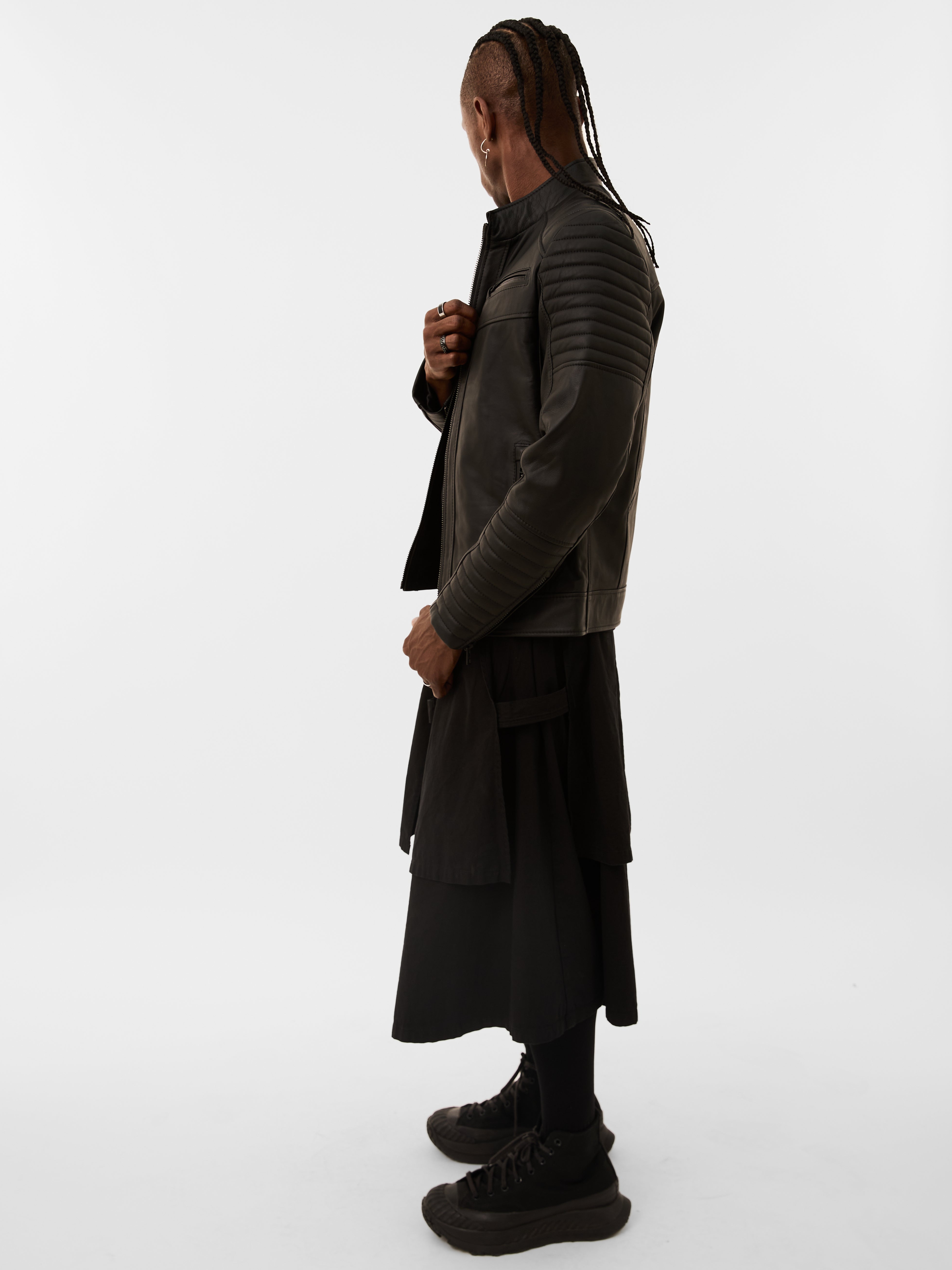 Person wearing a black quilted biker jacket and pants on a white background