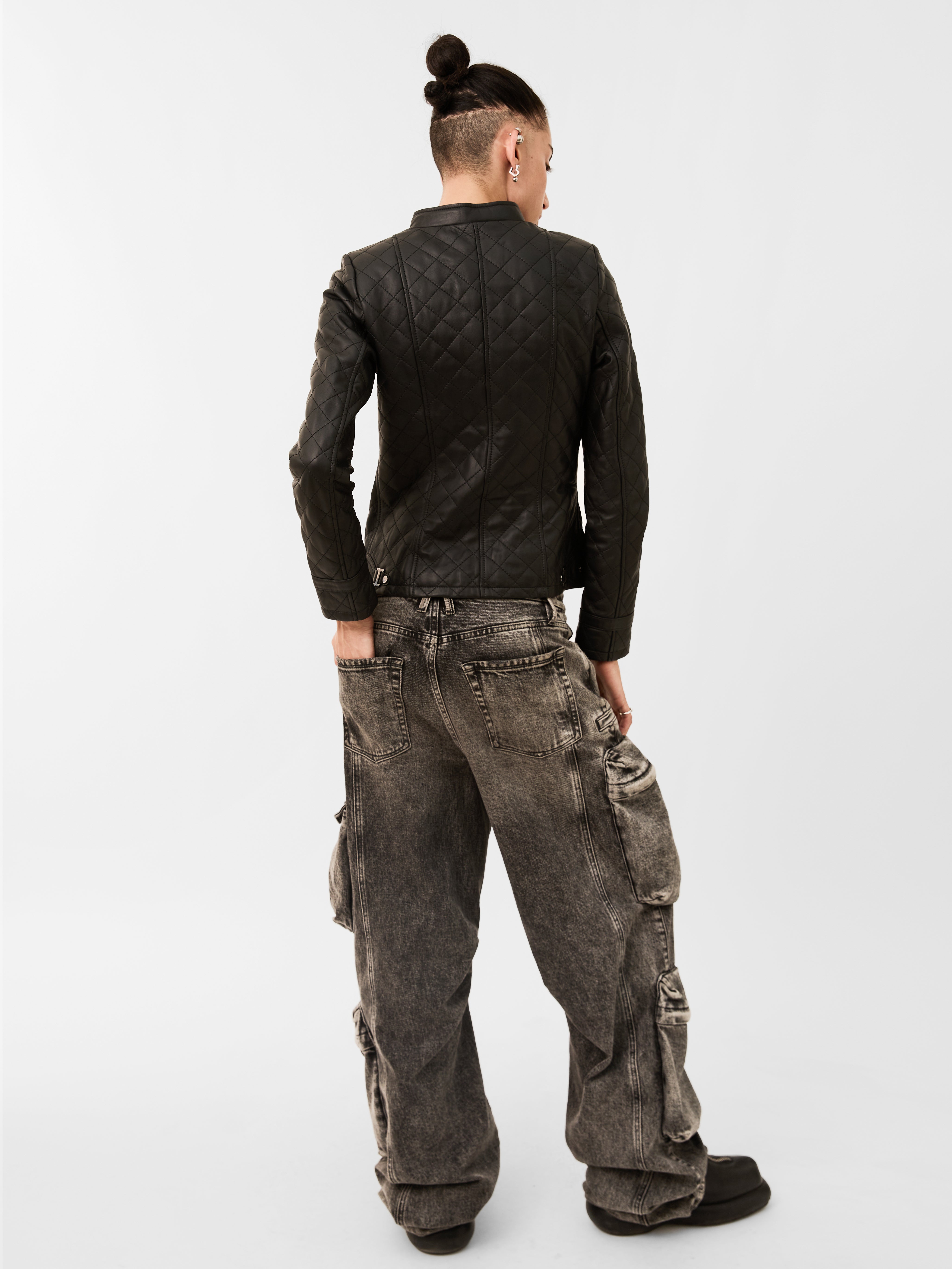 Person wearing a black jacket and gray cargo pants on a white background