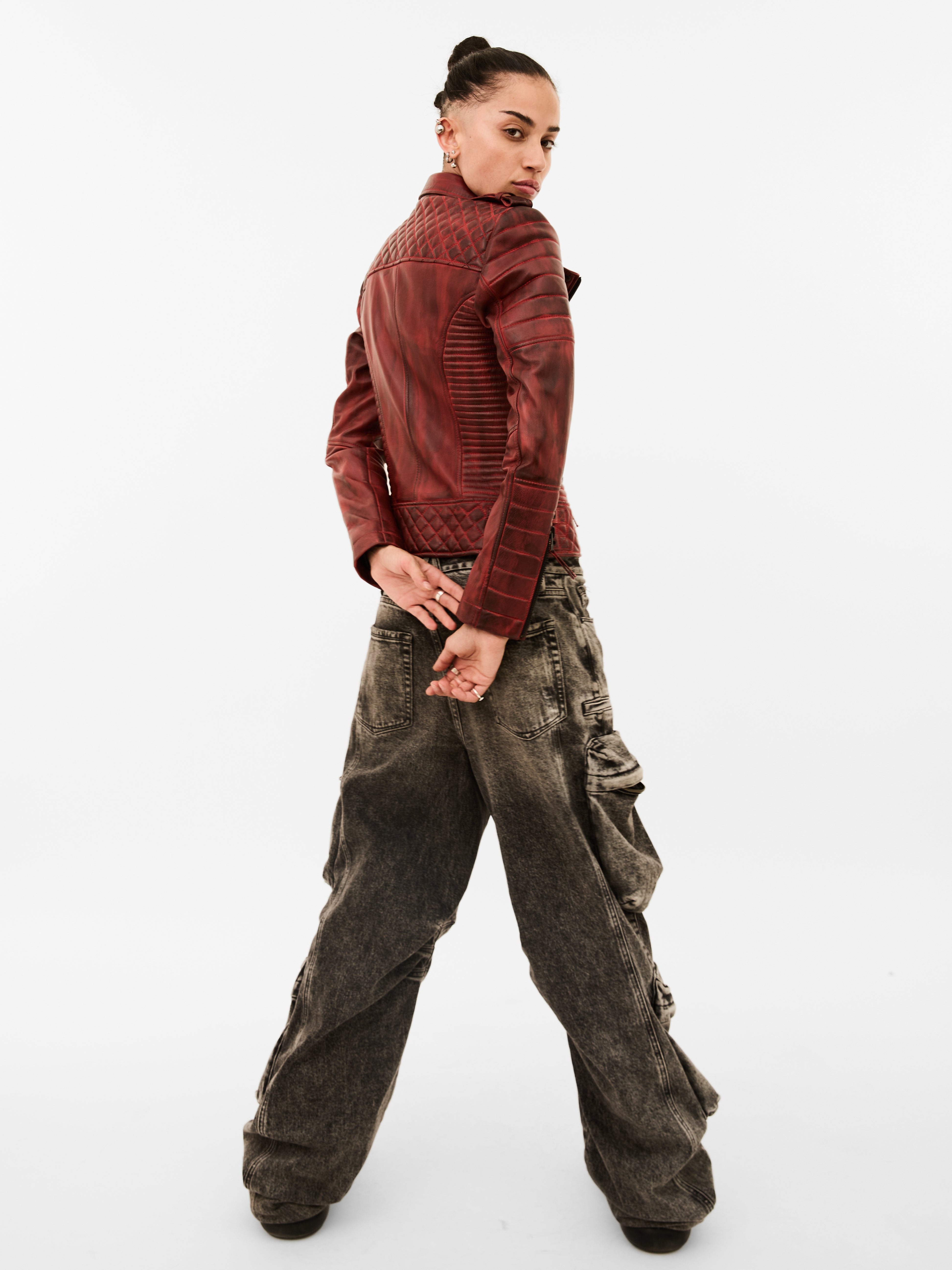 Person wearing a red leather jacket and baggy brown pants on a white background