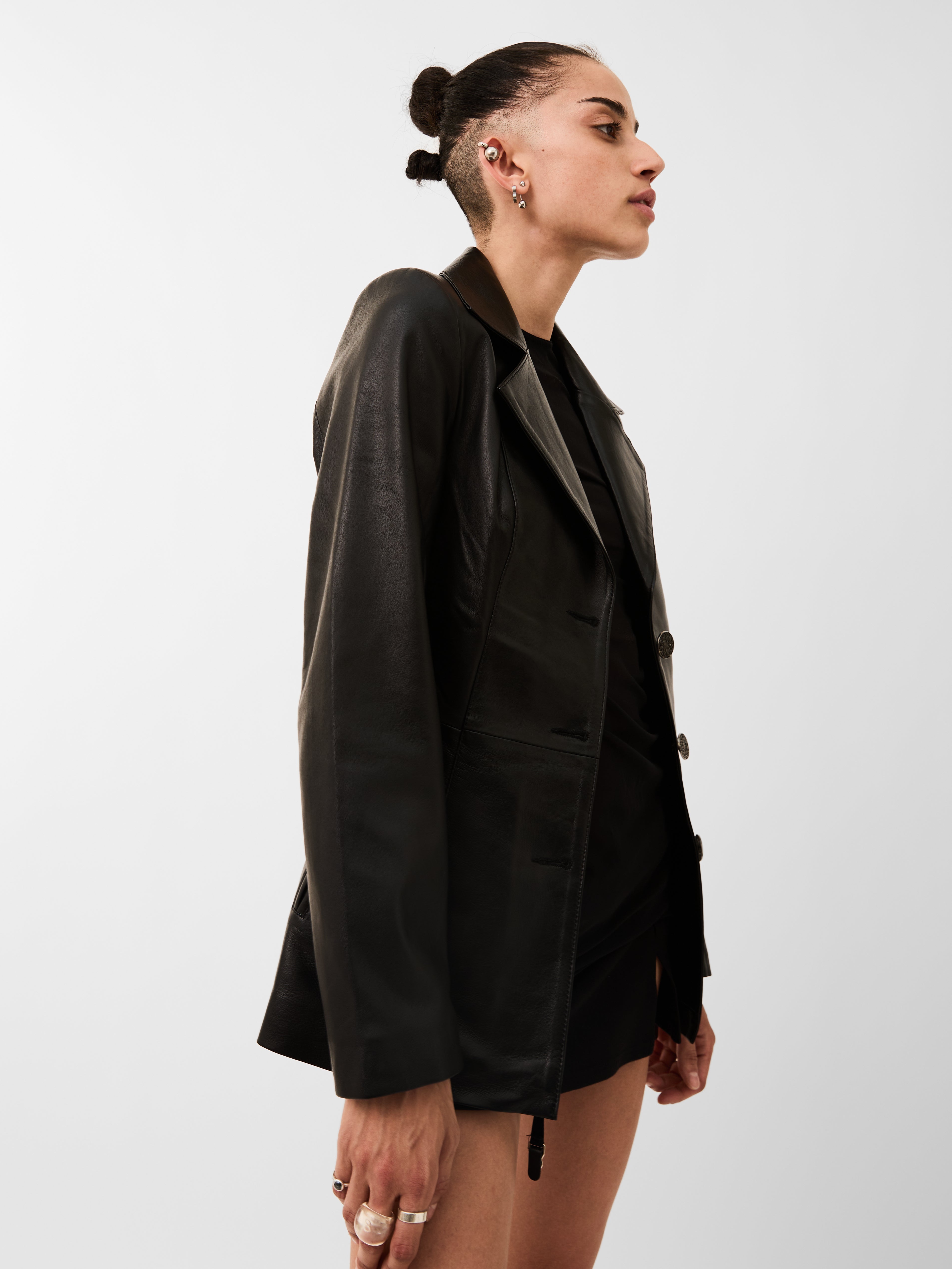 Person wearing a black blazer over a black top on a white background