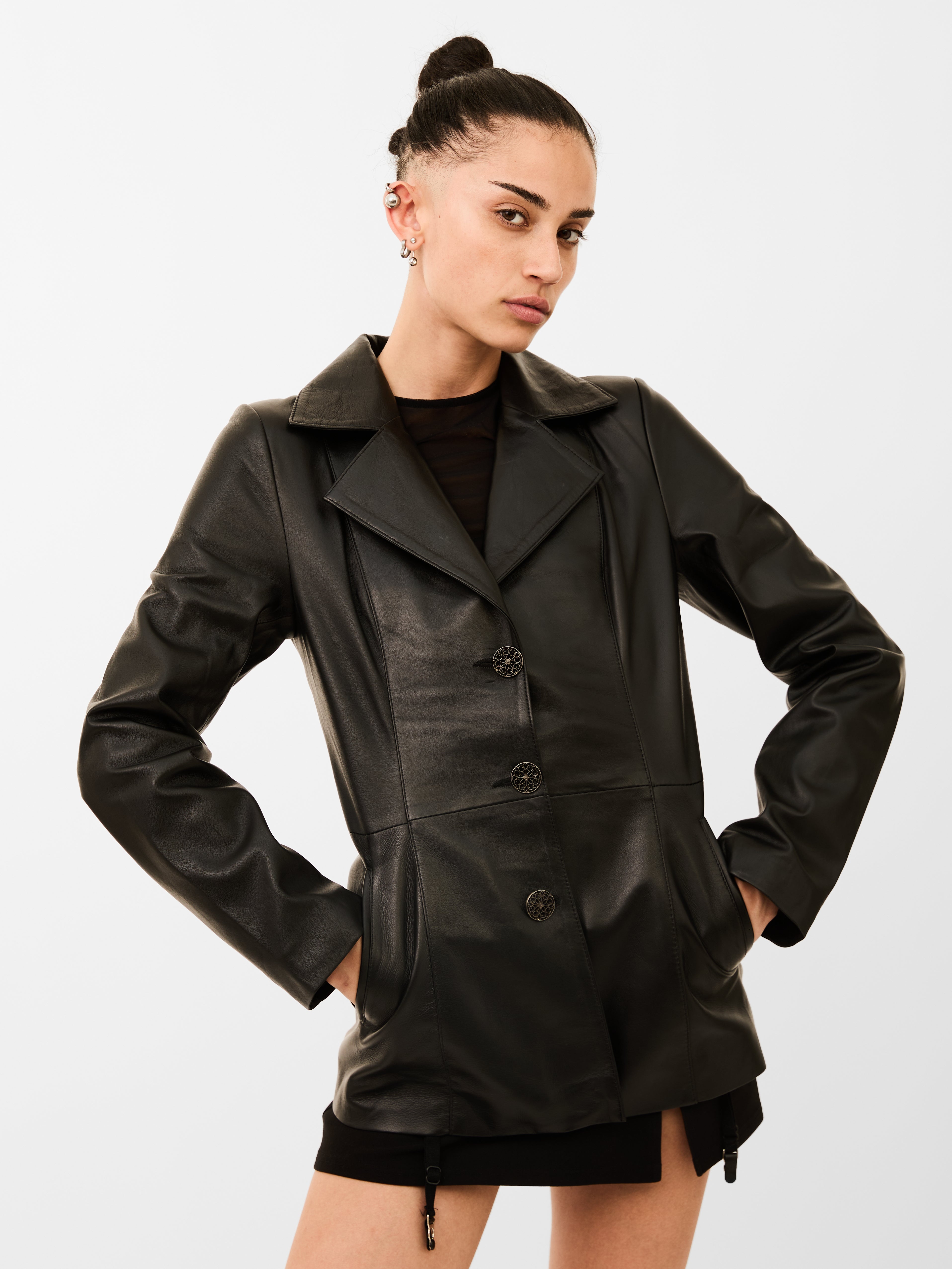 A woman wearing a black leather blazer jacket on a plain background
