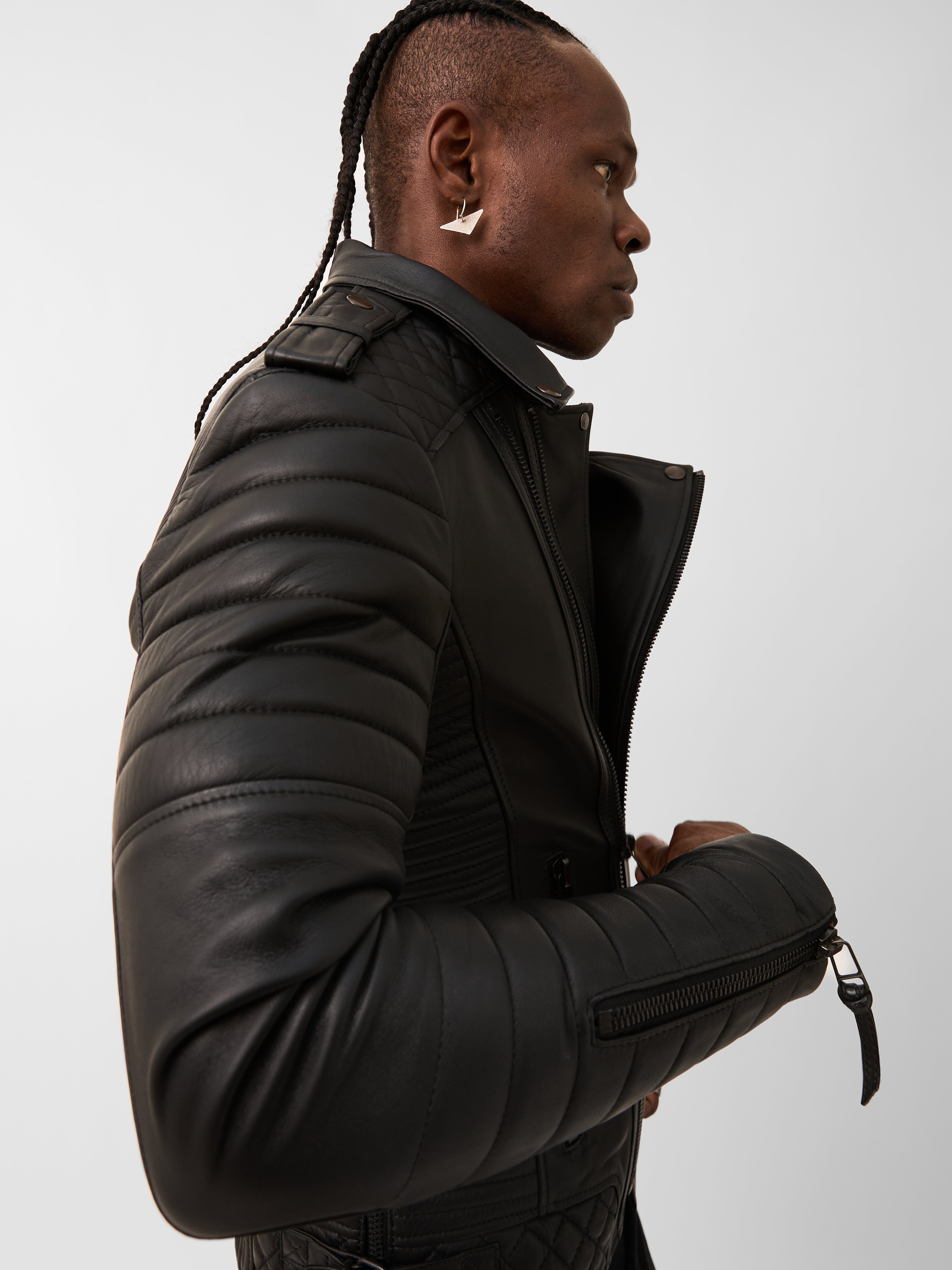 Man wearing a black biker leather jacket against a plain background