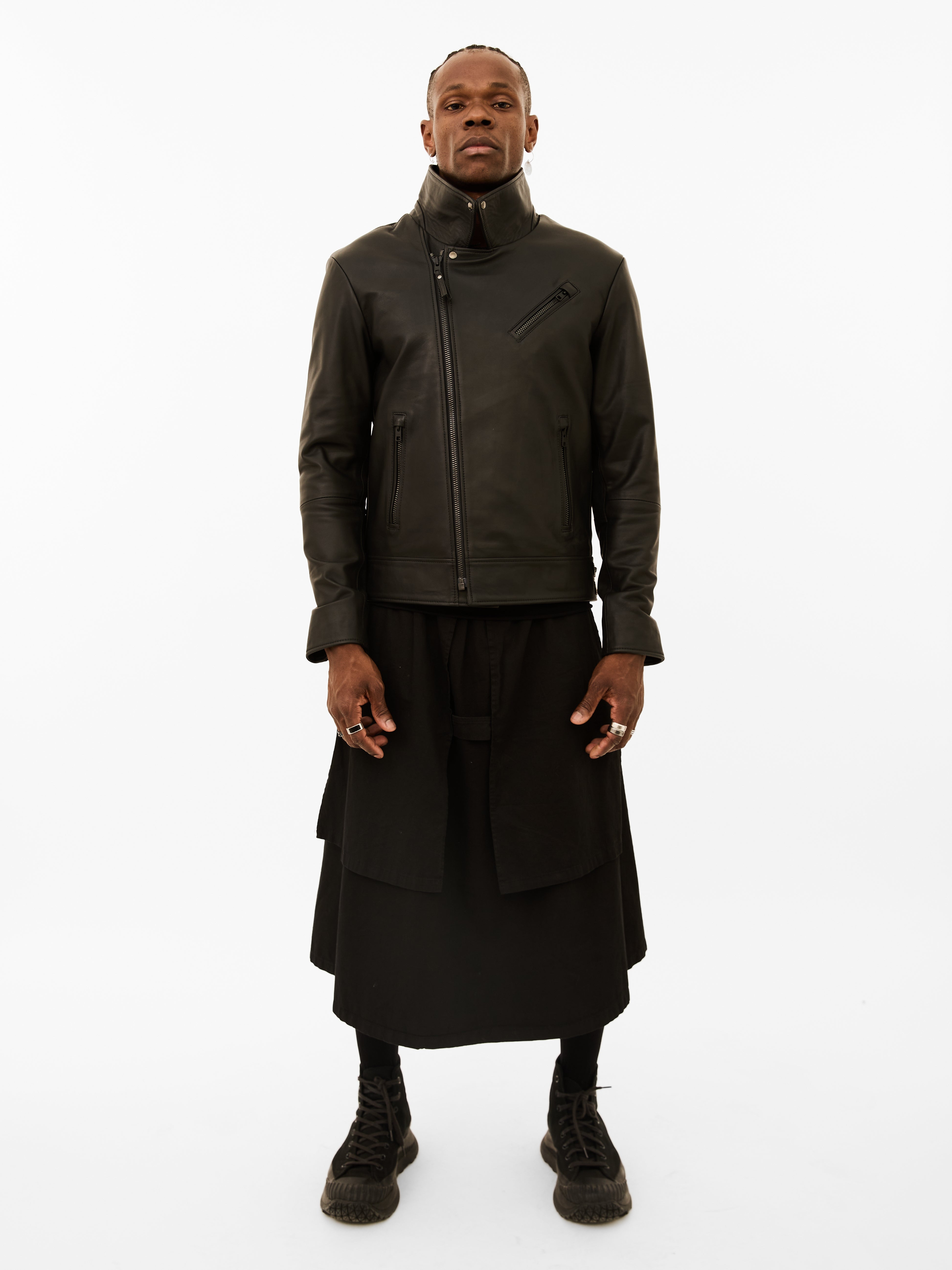 Person wearing a dark classic biker jacket and black skirt on a white background