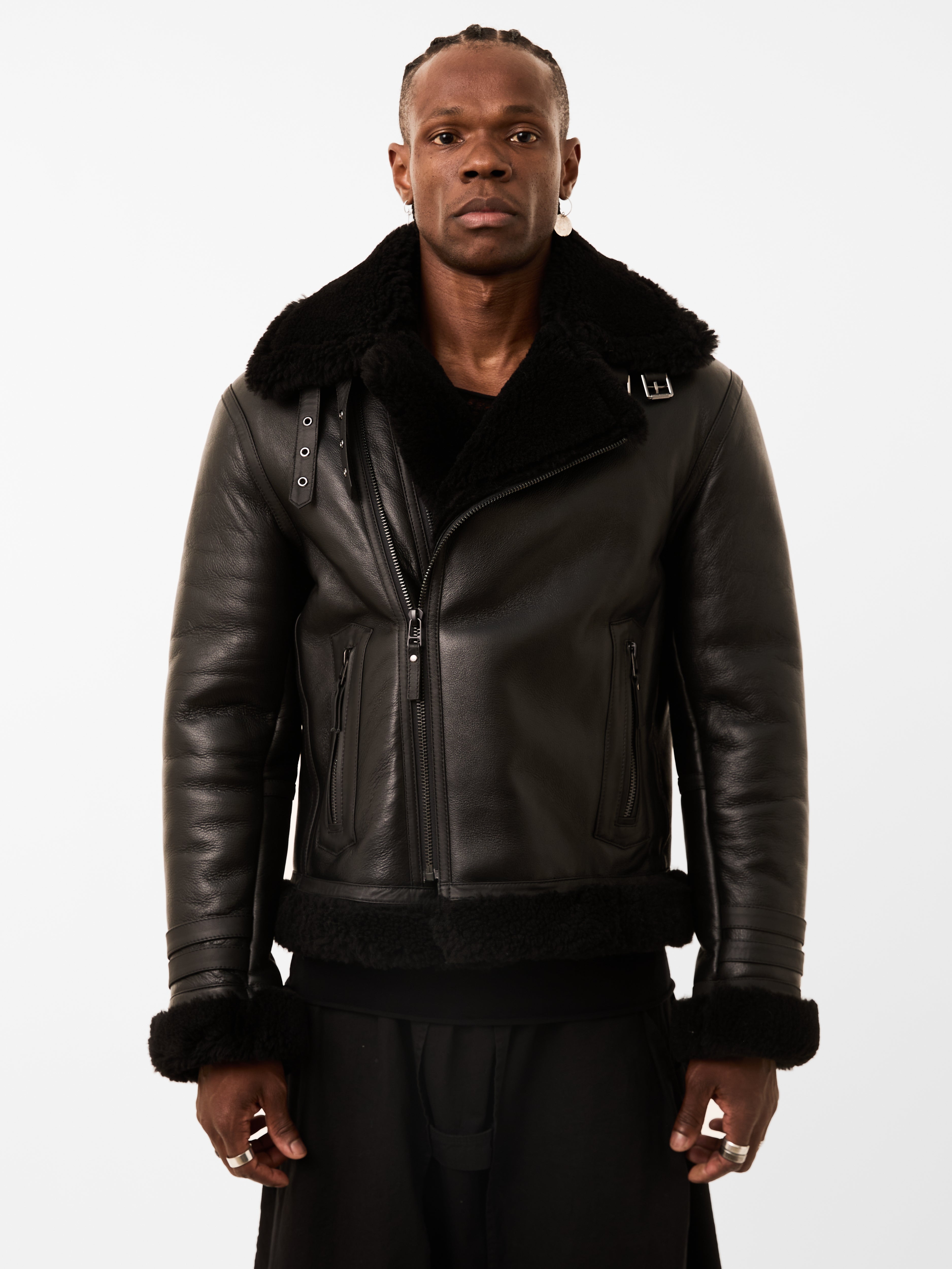 Man wearing a black leather jacket with fur collar on a white background