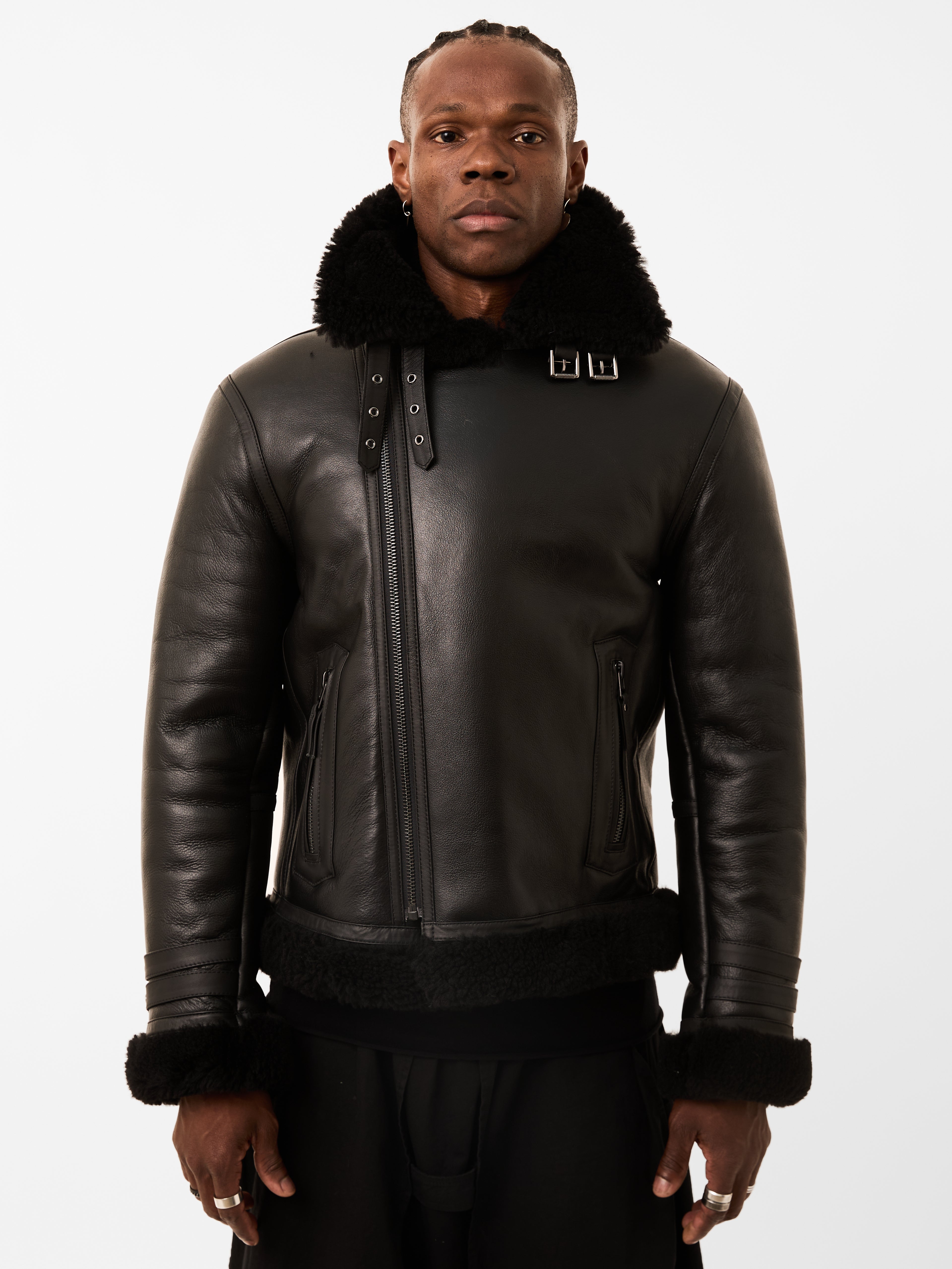Man wearing a black shearling leather jacket with fur trim on a white background