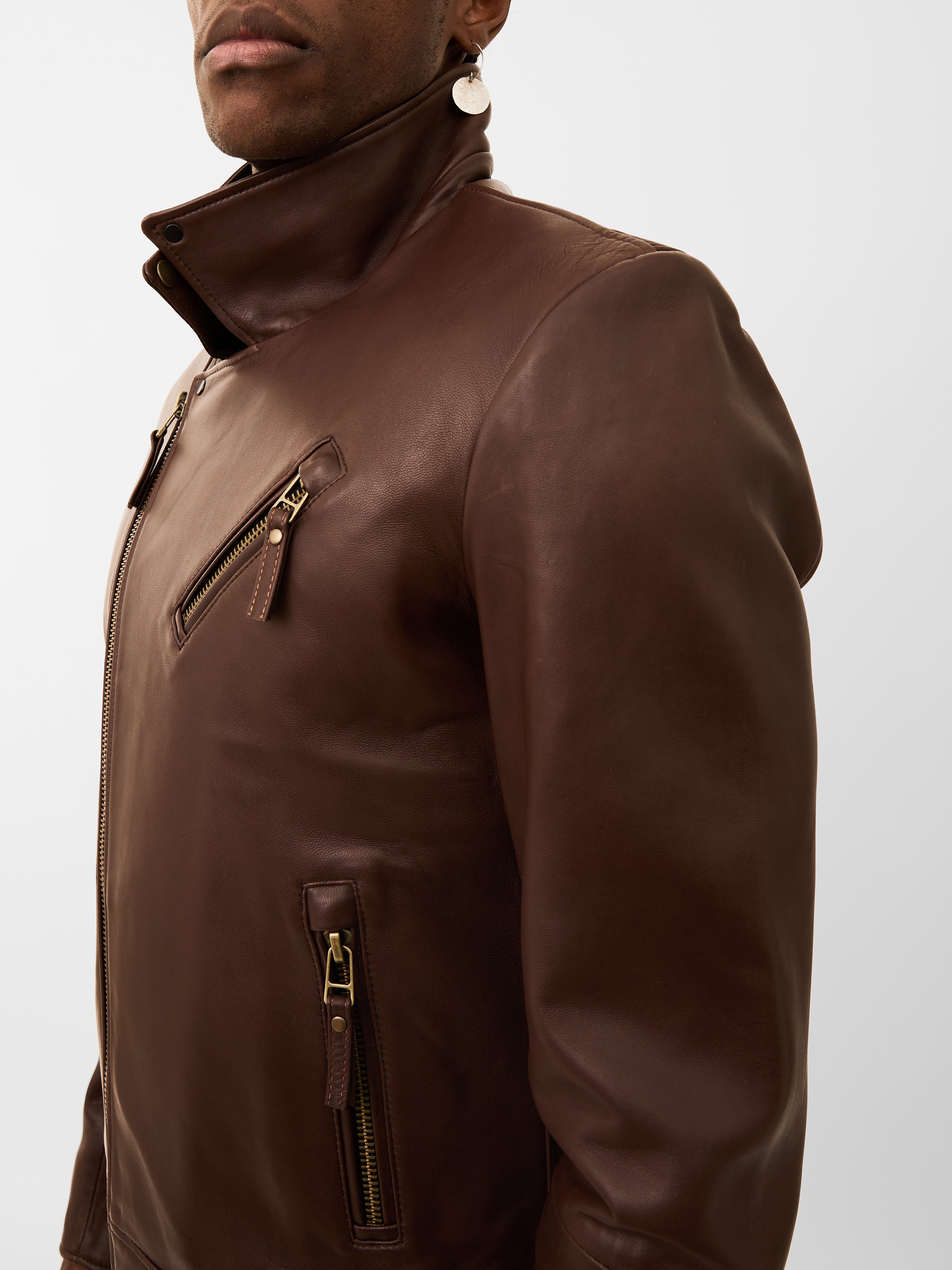 Brown leather jacket worn by a person on a white background
