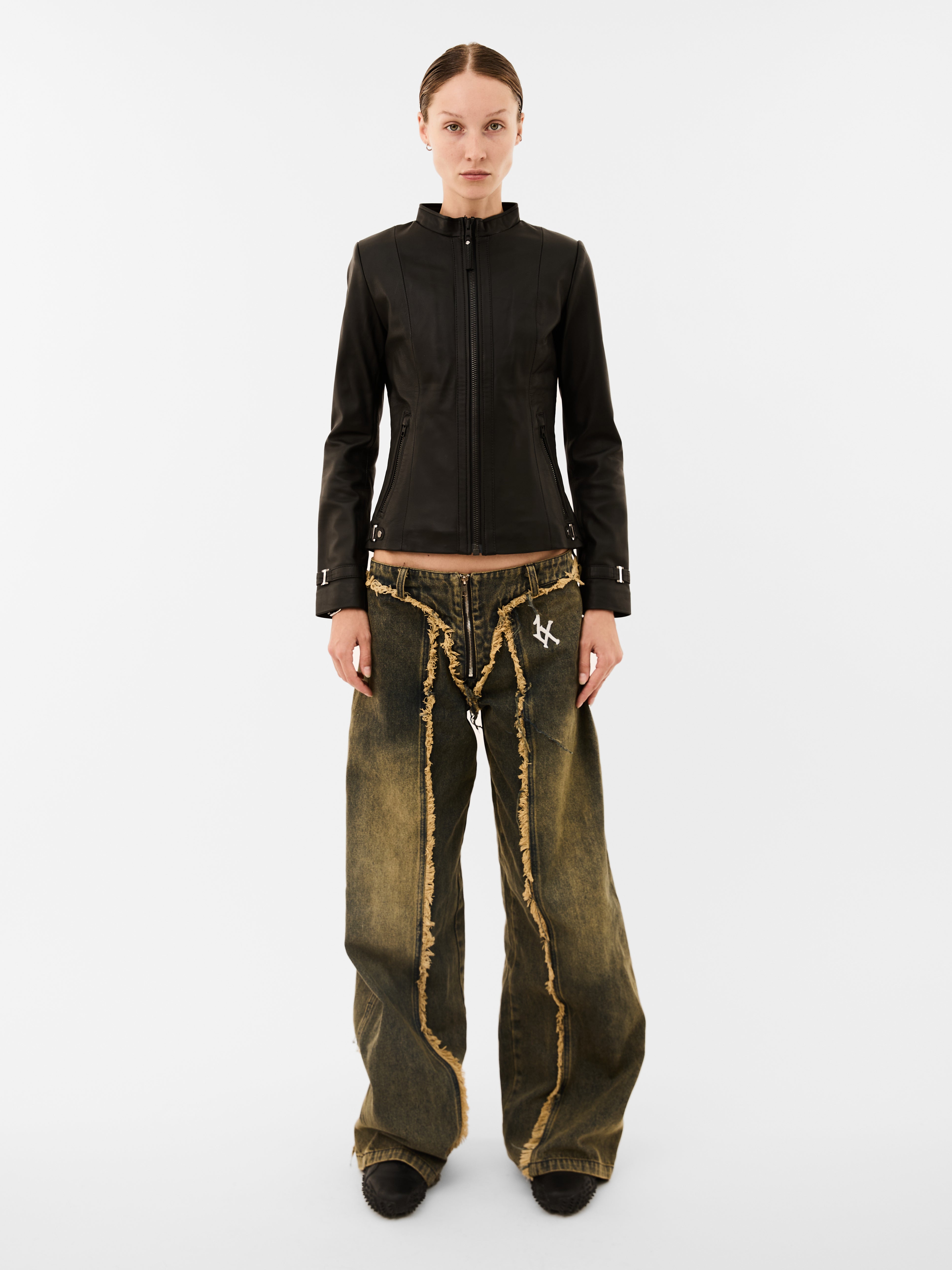 Person wearing a black jacket and distressed green pants on a white background
