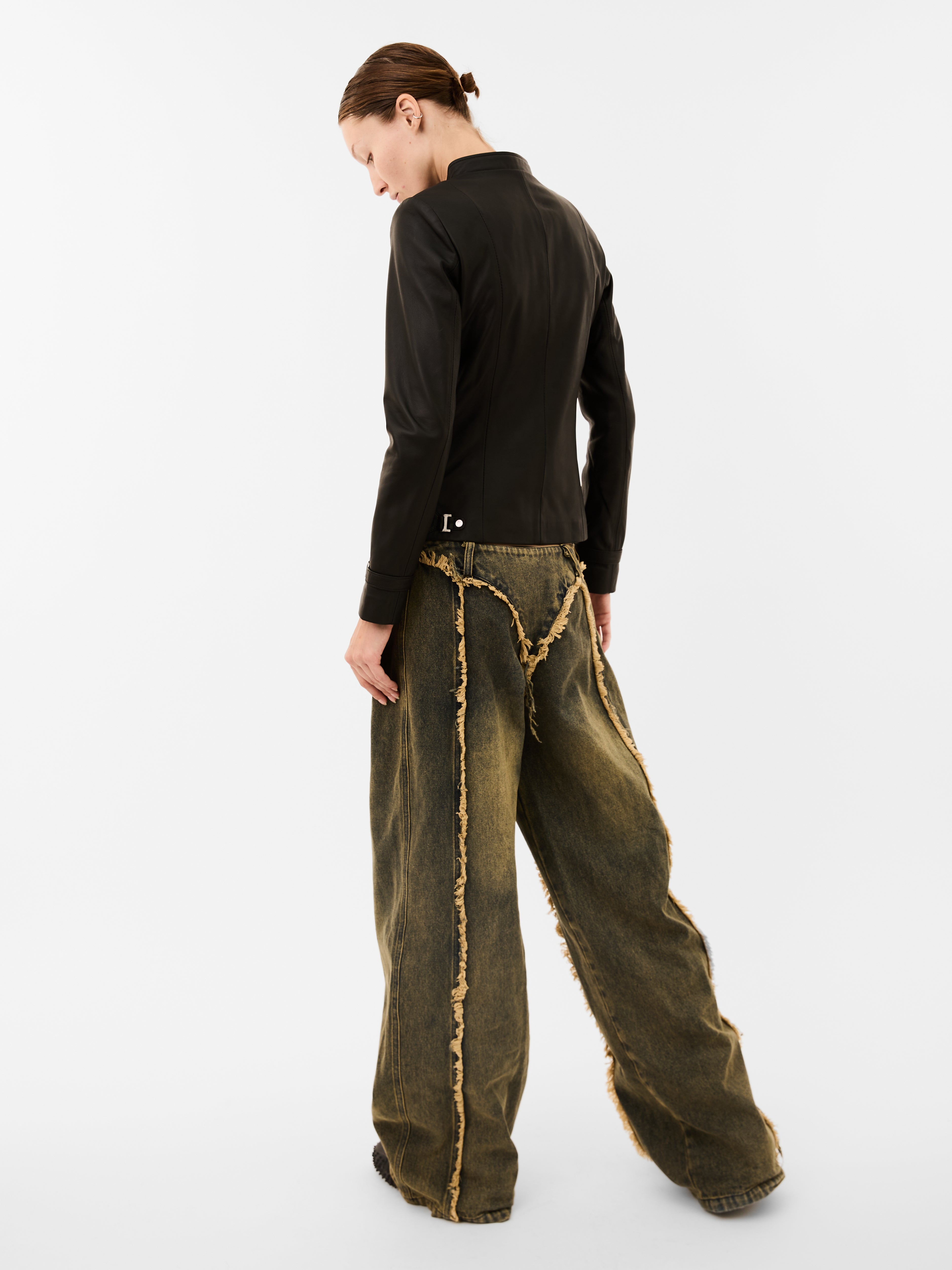 Person wearing a black top and green wide-leg pants with frayed edges on a white background