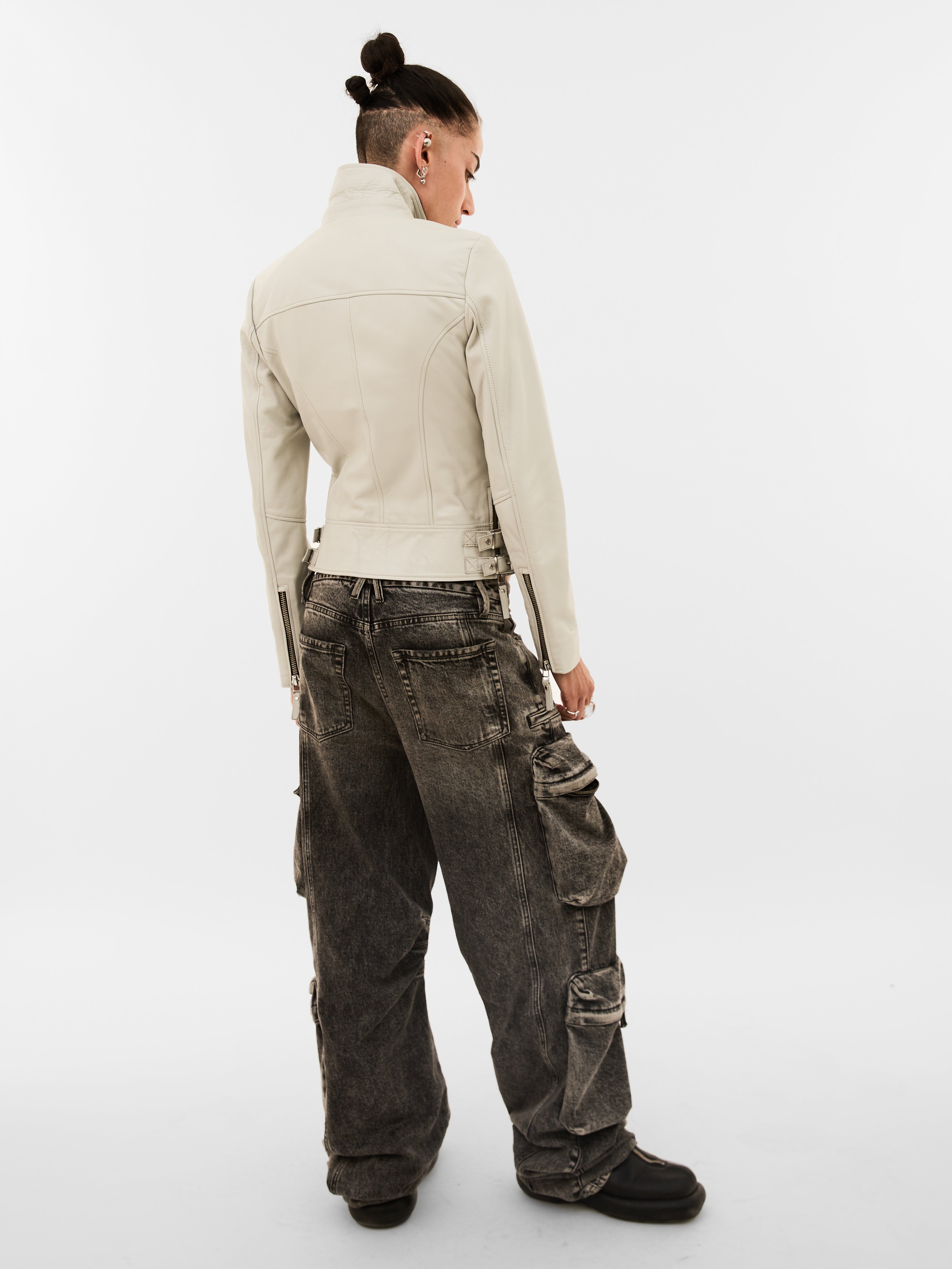 Person wearing a beige jacket and dark cargo pants on a white background