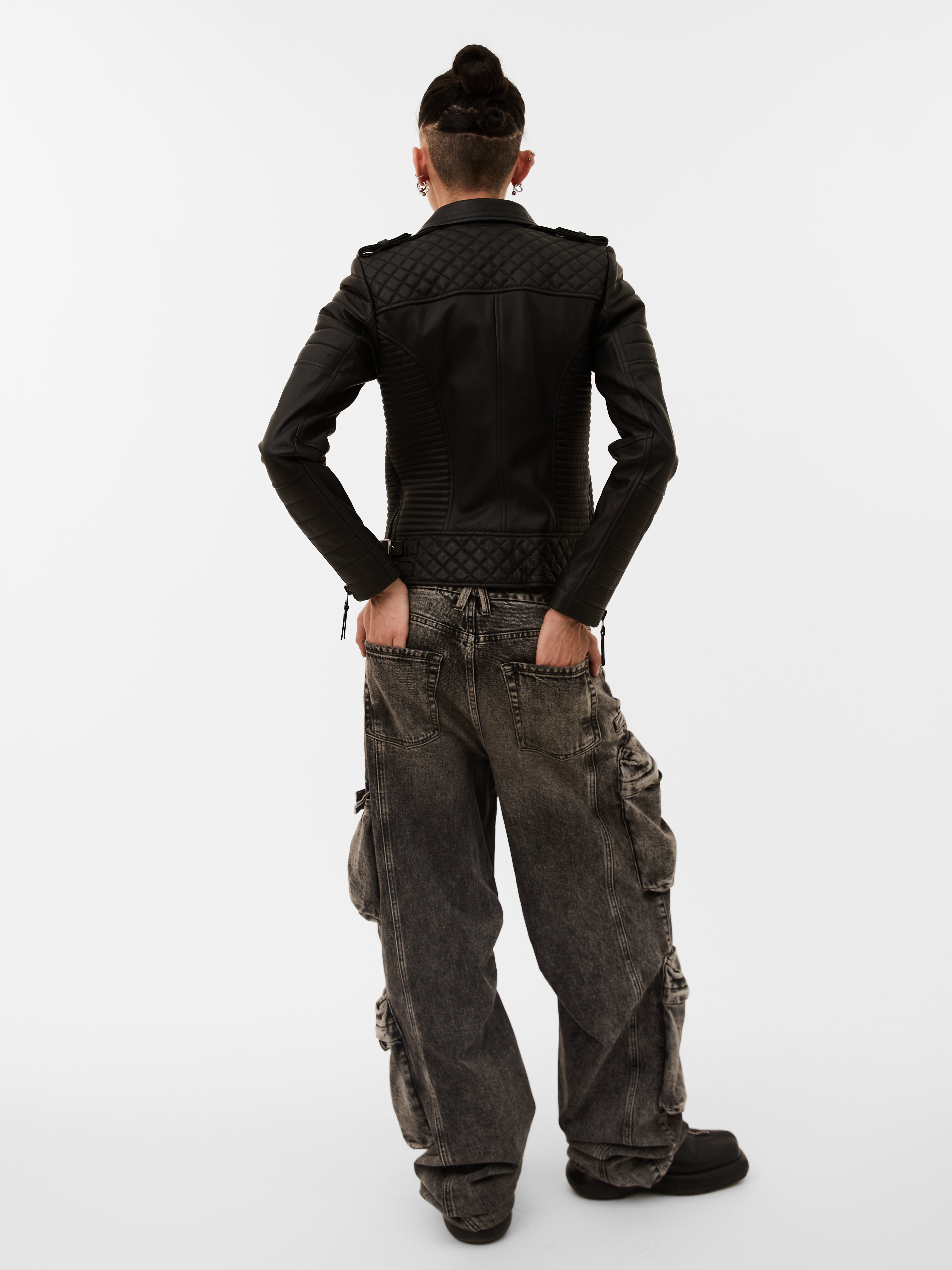 Person wearing a black jacket and gray cargo pants on a white background